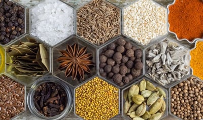 a variety of whole spices like anise and bayleaf along with some powdered spices in a clear tray