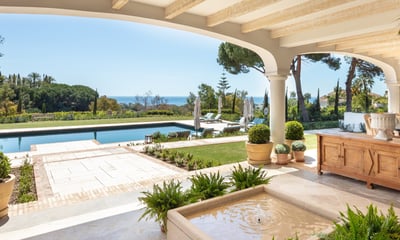 View from the shaded porch across the pool, with the Mediterranean Sea visible in the background.