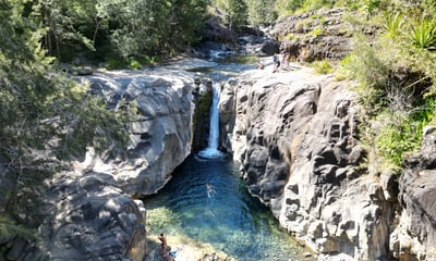 a waterfall in a canyon with a person standing on the side of it