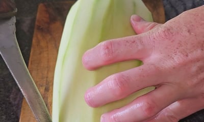 papaye verte avec un couteau et une main