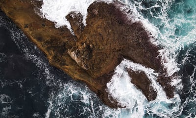 Un îlot est pris en photo du dessus par un drone, les vagues de la mer déferlent sur l'îlot