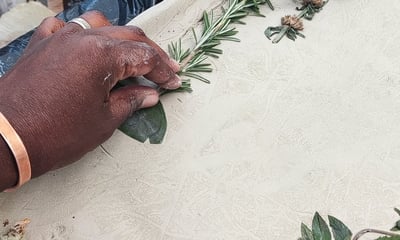 a person pressing a piece of rosemary in to clay