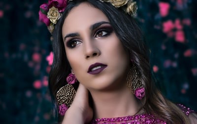 a woman in a purple dress and gold earrings