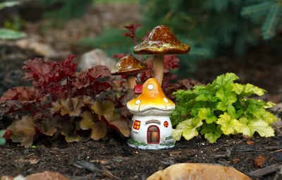 a small house with a mushroom house in the middle of the ground