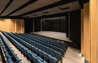 a theater stage with blue chairs and a stage