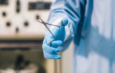 a person in a blue glove holding scissors