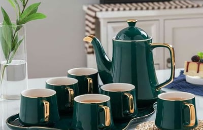 a teapot with cups of tea and a cake