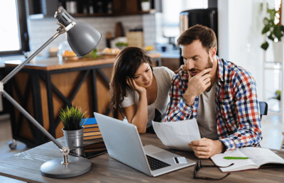 Casal trabalhando junto ao notebook, com semblante frustrado por não estar conseguindo resultados