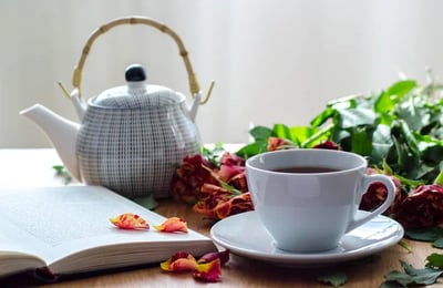 a teapot and tea cup with detox herbal tea and a book to journal your retreat