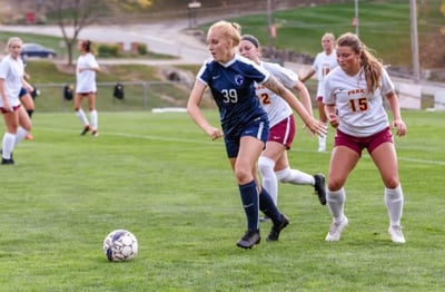 Women playing soccer holding the ball