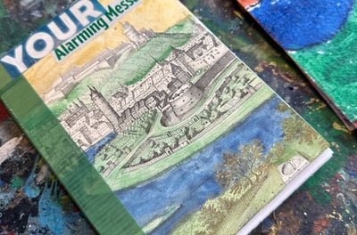 a handmade book with a hand-colored castle and moat on the cover