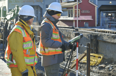 two men in safety vests standing in front of a building