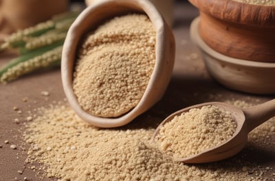 A pile of white flour sits on a wooden surface, accompanied by a wooden scoop and two sprigs of wheat.