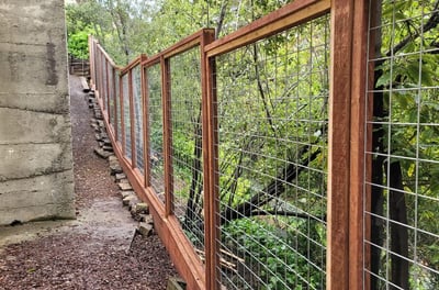 a tall hogwire redwood fence along a home