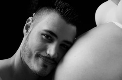 photo de grossesse avec le portrait du futur papa posant sa tête sur le ventre fond noir