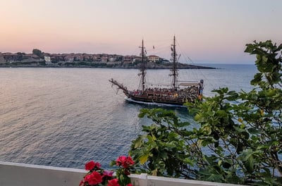 a boat sailing in the ocean at sunset