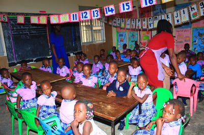 a woman standing in front of a classroom with a group of children