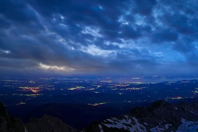 Säntis – Nachtansicht von oben mit Blick auf beleuchtete Städte und Wolken