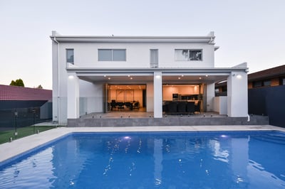 modern white home with outdoor entertainment and pool in foreground