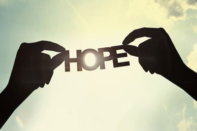 two hands holding up a piece of paper with the word hope written on it