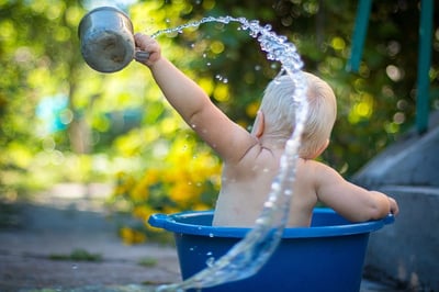 Picture of a baby in small tub having a wonderful time throwing water everywhere