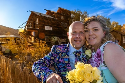 a man and woman standing in front of a wooden house