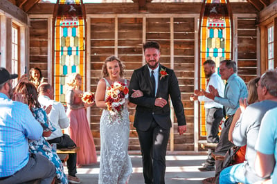 a man and woman walking down the aisle of a church