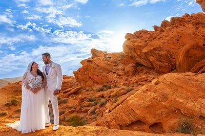 a bride and groom standing on a rocky mountain