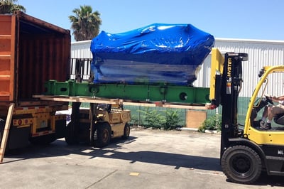 loading a large item with a large blue tarp into a truck 