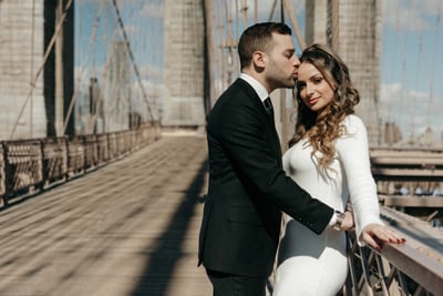 a bride and groom standing on a bridge