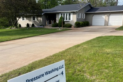Boss Pressure Washing LLC yard sign in front of a freshly cleaned driveway and home.