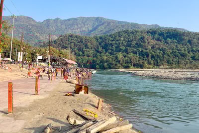View of the sacred Ganges River flowing through Rishikesh, India, with the Himalayan mountains in the background.