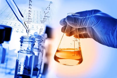 ma pessoa segurando um béquer contendo líquido alaranjado em um laboratório