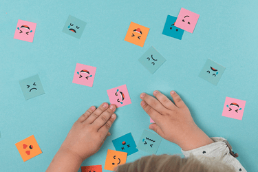image avec des mains d'enfant jouant avec des images d'émotions