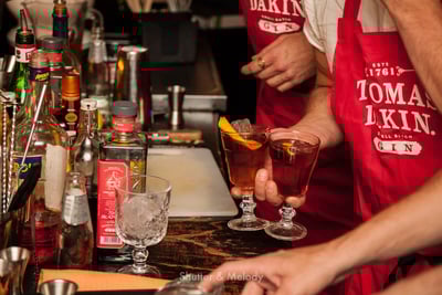 Ein Barkeeper trägt zwei Gläser mit Negronis weg.