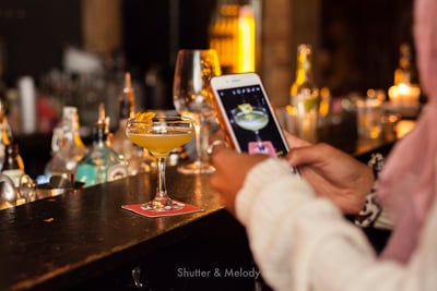 Ein Barkeeper macht ein Foto von einem Gin Sour.