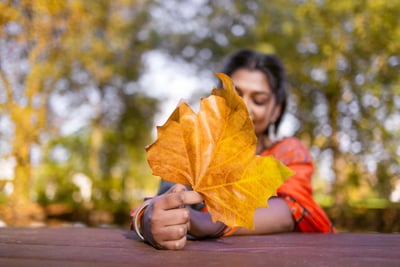 a woman holding a leaflet in front of a tree