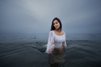 a woman in a white dress is standing in the water
