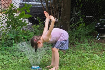 kid in backyard sprinkler
