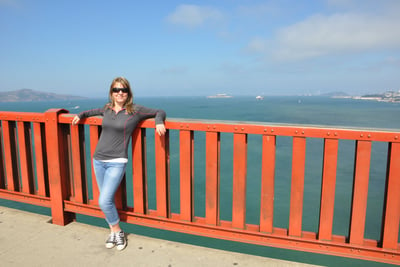 a woman standing on the golden gate bridge over looking at the ocean