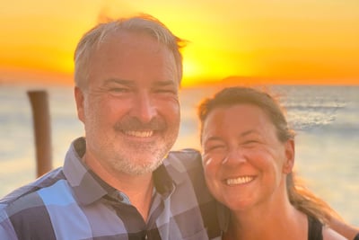 a man and woman standing in front of a sunset