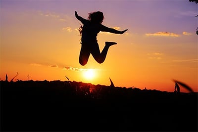 sunset background, silhouette human figure jumping for joy