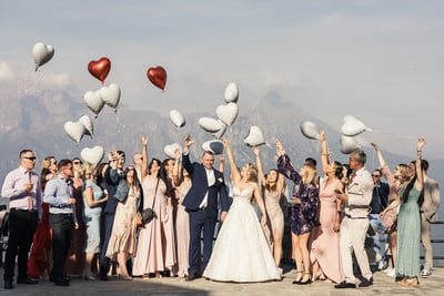 Grupowe zdjęcie pary młodej z gośćmi trzymającymi balony