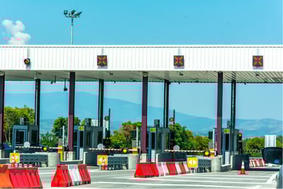 Toll booth with barrier, surveillance camera, and traffic lanes under smart toll control system.
