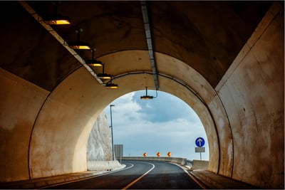 Inside view of a modern road tunnel with lighting and exit signage for smart monitoring and evacuation control.