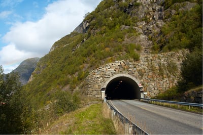 Stone-structured tunnel entrance on a mountain road for rural tunnel traffic and safety monitoring solutions.
