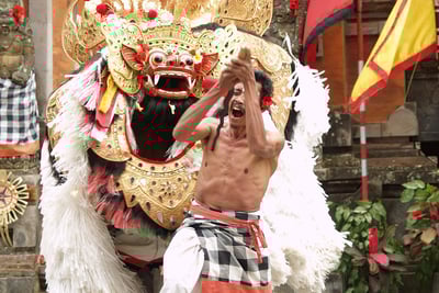 a man in a kiltly costume is holding Barong Dance