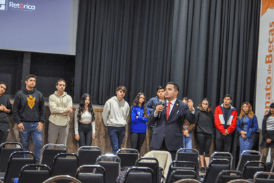 a man in a suit and tie standing in front of a crowd of people