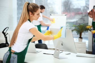 a woman cleaning a computer screen in a room