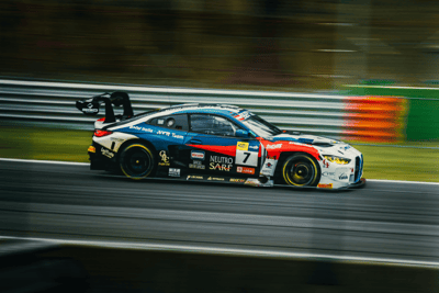 Auto GT in pista durante una gara ad alta velocità, con livrea sportiva e sponsor visibili